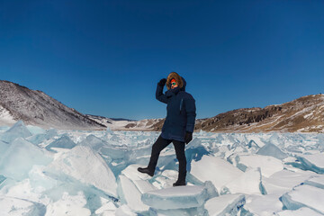 Portrait of the man tourist in red cap and blue jacket wearing sunglasses on ice