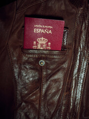 A Spanish passport in a brown leather jacket pocket