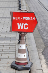 Direction Arrow Men Woman WC Sign Traffic Cone at City Street