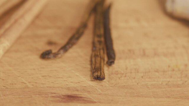 Vanilla sticks on a wooden table. Close up, macro. Slow motion handheld shot. Detail. Studio shot, kitchen. Bright lighting. High quality 4k footage