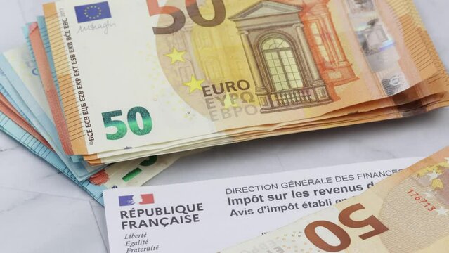 feuille d'imp&ocirc;ts fran&ccedil;aises et tas de billets de banque en euros. En gros plan.