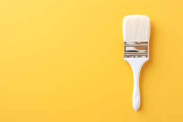 White paint brush on yellow background. Top view. Copy space.