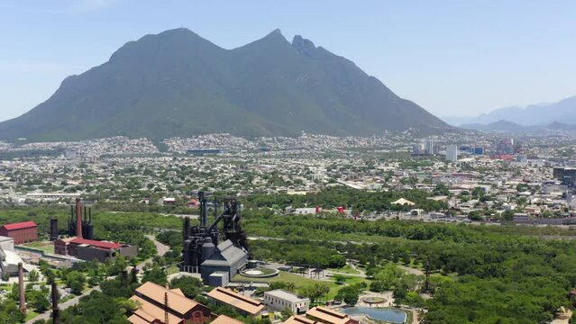 Aerial Panning Shot Of Museo Del Acero With Landmark Near Mountains Against Sky On Sunny Day - Monterrey, Mexico