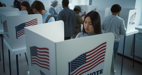 Asian woman comes to vote in booth in polling station office. National Election Day in the United...