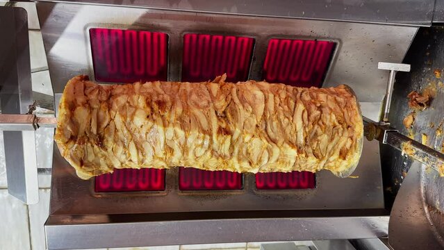 Preparing to cook Doner Kebab in restaurant, shawarma grilled skewered chicken on spit, closeup. Concept of Turkish, greek or middle eastern food. Street food 