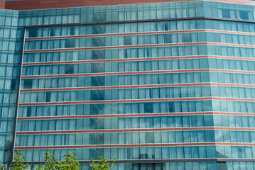 Close-up modern high rise hotel with glass wall blackout curtains against sunny cloud blue sky in Texas, lookup view office building, skyscraper, futuristic looking architecture