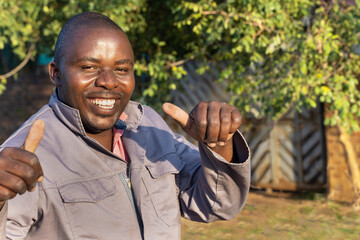happy african worker with a smile holding thumbs up, outdoors in a sunny day,