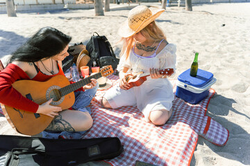 Alternative girls on beach picnic playing guitar