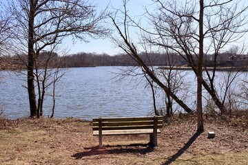 The empty bench on the shore at the lake.