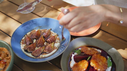 Lady hands taking hummus with figs from blue plate at cafe closeup. Woman eating