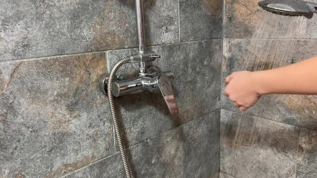 woman's hand opens the hot and cold water tap to water for bathing. Close-up of a beautiful faucet
