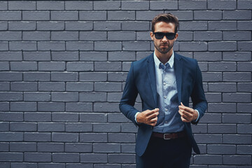 Confident, man and wall in suit with sunglasses for fashion, style and trendy in outdoor. Male...