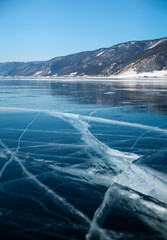 Texture of beautiful blue ice with cracks and air bubbles in the frozen Lake Baikal