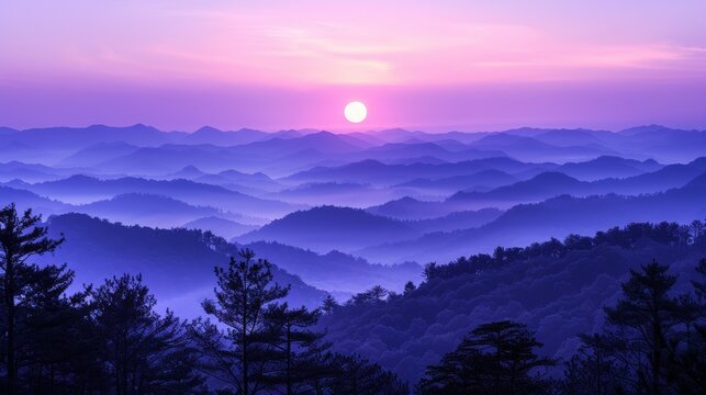 A beautiful landscape image of a mountain range at sunrise. The sky is a deep purple color, and the sun is a bright yellow orb. The mountains are covered in a blanket of fog, and the trees are a dark
