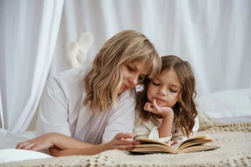  Reading the book together. Mother with daughter are at home © standret