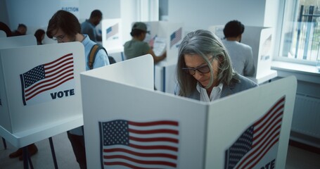 Elderly woman votes in booth in polling station office. National Election Day in the United States....