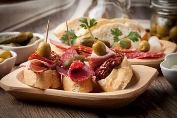 Tapas with sliced sausage, salami, olives and parsley. - 788370580