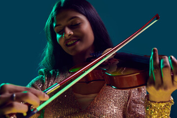 Enthusiastic musician, Beautiful Indian woman in sequined attire playing violin in neon light...