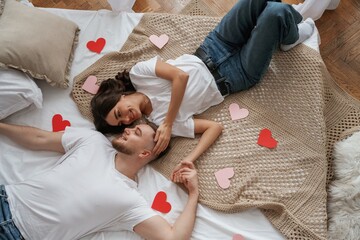 A lot of heart shaped paper decorations, top view. Young couple are together at home