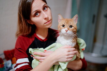 Woman holding wet cat after bathing.
