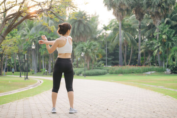 Female sportswoman. Fit young Asian woman with sportswear stretching muscle in park before running and enjoying healthy outdoor. Fitness runner girl in public park. Wellness being concept - 788388325