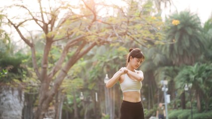 Shoulder pain problem. woman jogger. 30s asian female wearing white sportswear holding her shoulder with pain after running exercise in public park. - 788388344