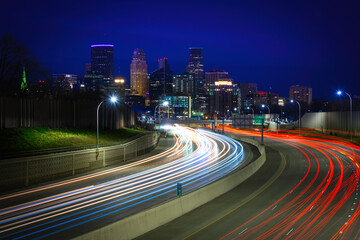 Minneapolis City Skyline, skyscrapers, and illuminated office buildings at night over I-94 Interstate Highway with light trails of cars in Minnesota, USA
