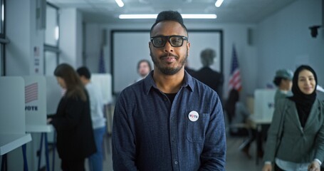 Portrait of African American man, United States of America elections voter. Man with badge stands...