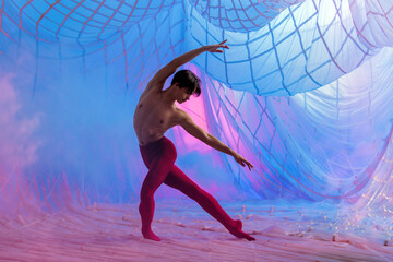 A man in a red outfit is dancing in front of a blue background.