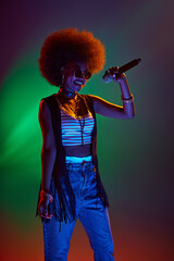 Talented vocalist with stylish afro hair performing jazz songs in neon stage light against gradient...