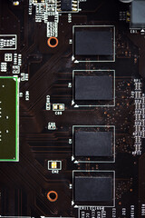 A brown printed circuit board with a processor chip and video memory strips. Electronic components...