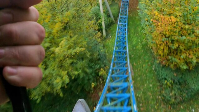 Experience the heart-pounding excitement of a roller coaster ride captured from a first-person perspective. As the coaster ascends and rapidly descends along the vibrant blue track, riders are