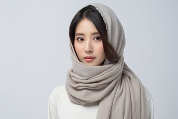 An adorable Asian woman wearing a coat, and a gray scarf is looking at the camera while smiling with a face which is full of cheeriness and liveliness. Generative AI.
