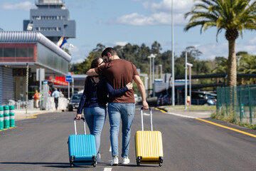 couple with yellow and blue suitcase at the airport waiting for the plane to enjoy their vacation