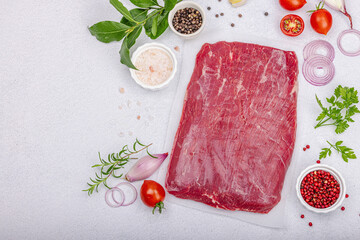 Dry aged Bavette steak with traditional spices and herbs. Fresh raw meat cut, light stone background