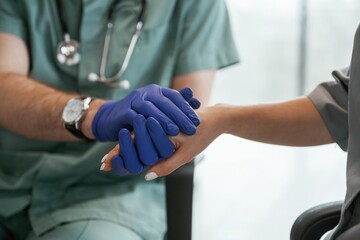 Blue gloves. Two doctors are holding hands indoors