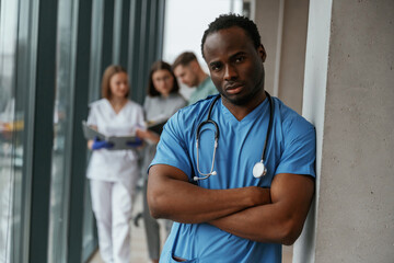 African American man is standing in front of colleagues. Group of doctors are together indoors