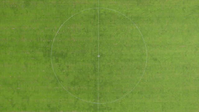 This high-angle drone footage presents the immaculate condition of a soccer field, with its vibrant green turf and distinct white boundary lines. The aerial perspective highlights the geometric