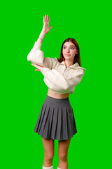 A woman dressed in a skirt and sweater is standing and waving her hand in the air, possibly in a greeting or to get someones attention. - 788420364