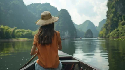 Foto op Canvas Young woman views Mountain View while sitting on a rowboat in Ninh Binh, Vietnam. © suteeda
