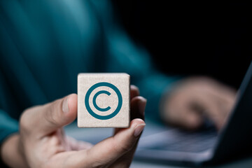 Person holding wooden block with copyright icon for author rights and patented intellectual property. copyleft trademark license. Copyright or patent concept.