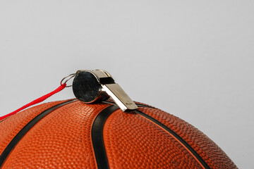 Close-Up View of a Whistle Resting on a Basketball Against a Grey Background