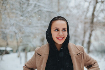 Young positive woman with funny smile on her face stands outside against background of winter forest
