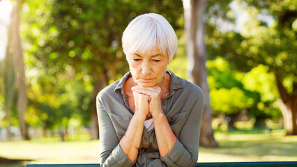 Old woman, praying or thinking in park, sad with grief or loss, dementia diagnosis and health scare...