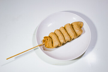one spoonful of odeng food, served on a plastic plate with a plain white background