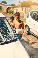 Boy, carwash and vehicle in home, soap and driveway with help of family. Child siblings, bonding or...