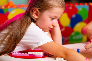 Curly-Haired Toddler Girl Concentrating on Building With Colorful Blocks Indoors - 788465527
