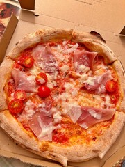 fresh pizza with tomatoes, arugula, ham, Italian pizza with mozzarella and tomato sauce, pizza to order, pizza in cardboard boxes