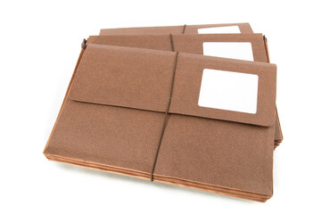 a stack of three brown accordion file folders with blank labels isolated on white