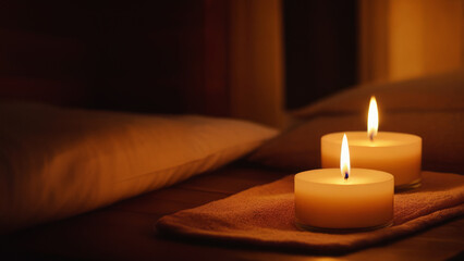 Obraz na płótnie Canvas A peaceful and relaxing atmosphere with burning candles and a towel on a dark background. Relaxing evening in a cozy Thai resort. Concept of calm and harmony.